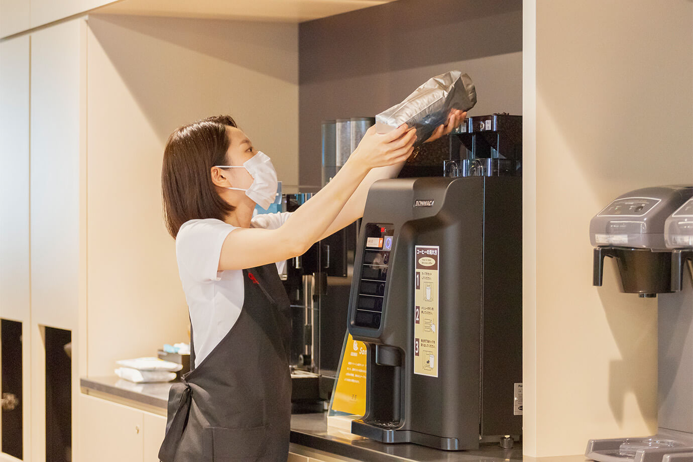 女性スタッフがコーヒ豆を入れ替える様子